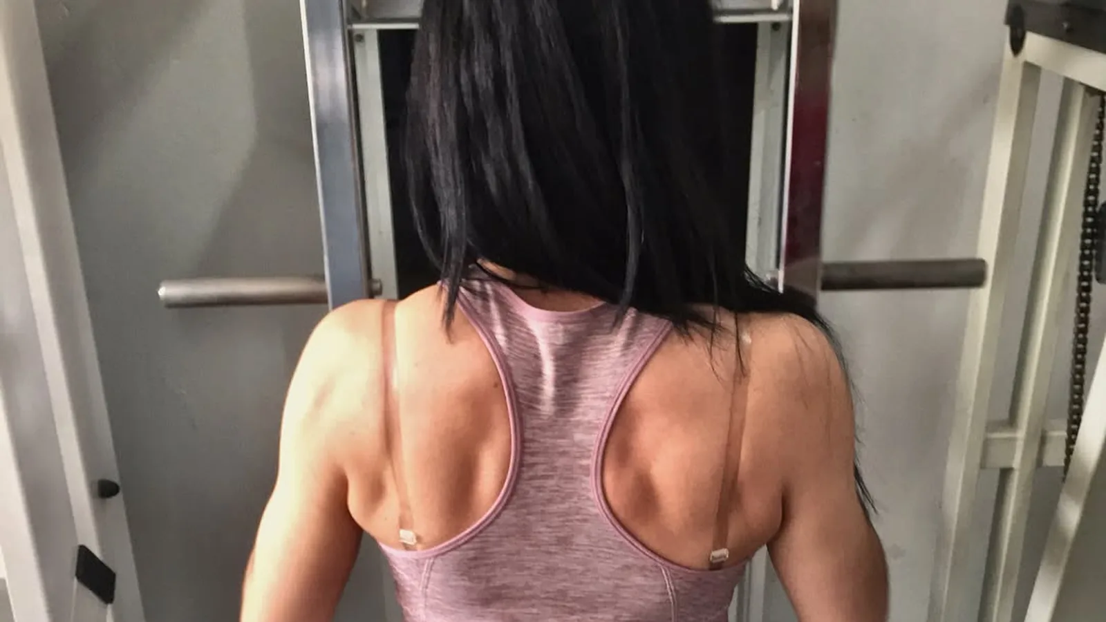 Una clienta d'esquena a la màquina de dorsals, a la sala de musculació