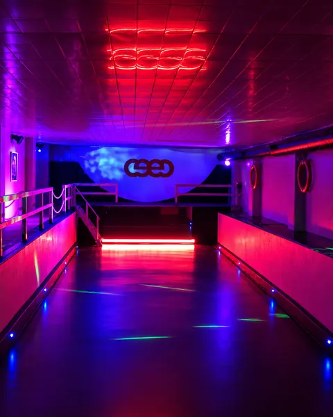 La sala d'activitats buida, amb els llums morats i vermells encesos i el logo del CEEC al fons