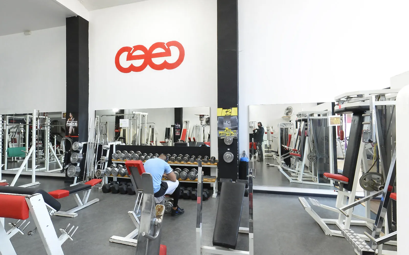 La sala de musculació: màquines blanques i vermelles, les manuelles i el logo pintat a la paret