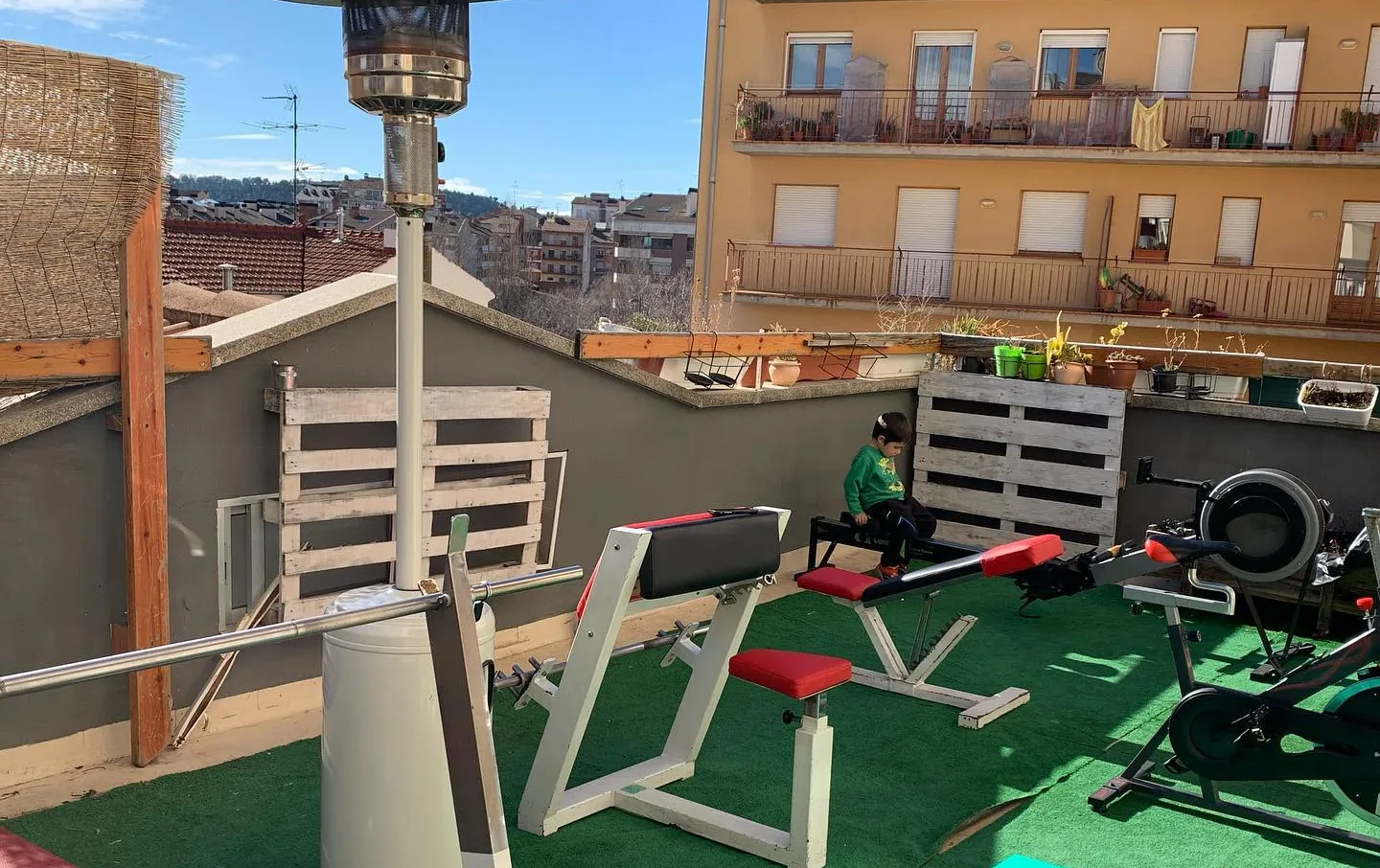 La terrassa amb gespa artificial, un banc i màquines a l'aire lliure